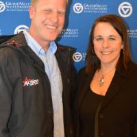 two people pose for picture in-front of grand valley banner